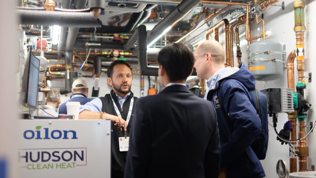 Ian Motley of Hudson Clean Heat explains an Oilon heat pump system to visitors inside a mobile electrification demonstration lab