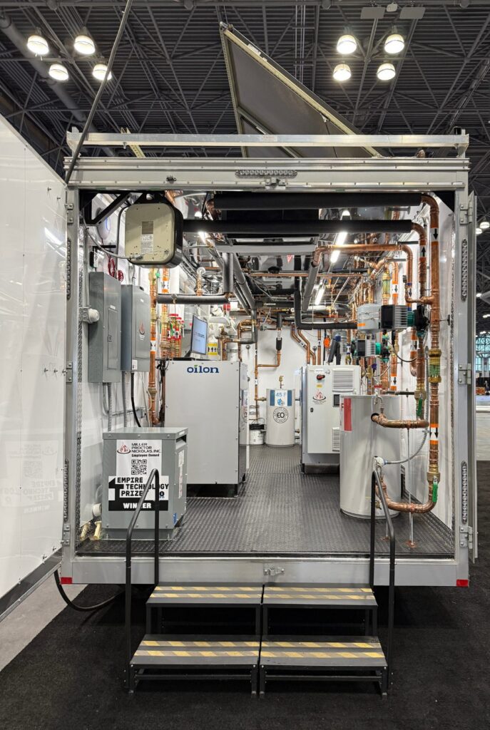 Inside a mobile building electrification demonstration trailer with an Oilon heat pump, copper hydronic piping and domestic hot water tanks